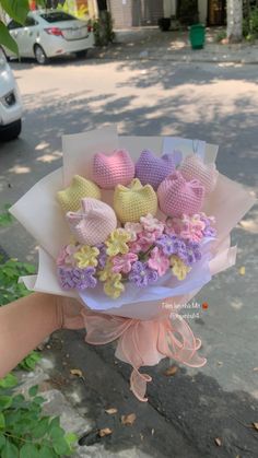 a person holding a bouquet of crocheted hearts in their hand on the street