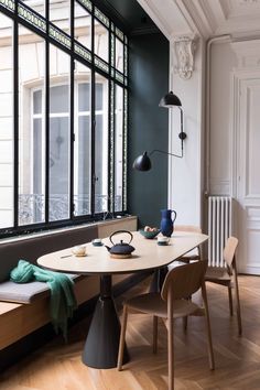 a dining room table with two chairs and a bench in front of a large window