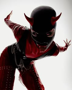 a man dressed in red and black with horns on his head is performing an acrobatic dance