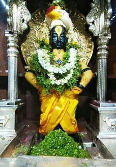 a statue of lord ganesha with flowers on his head and arms in front of him