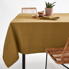 a table with a brown cloth on it next to a chair and potted plant