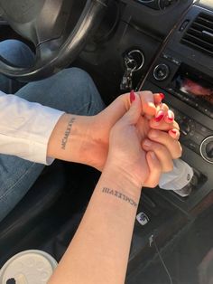 two people holding hands while sitting in a car with the steering wheel and dashboard light on