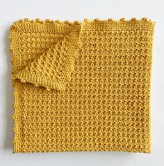 a yellow crocheted cloth on a white surface