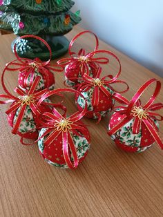 six christmas balls with bows on them sitting on a table next to a small tree