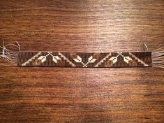 a brown and white beaded bracelet sitting on top of a wooden table