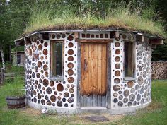 a round building with a grass roof and windows on the outside is made out of rocks