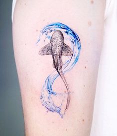 an octopus tattoo on the back of a woman's left arm, with water swirling around it