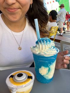 a woman sitting at a table with an ice cream sundae and minion drink