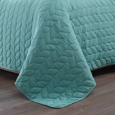 a bed with a green comforter on top of it