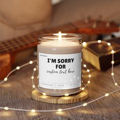 a candle that is sitting on a table with some string lights and a guitar in the background