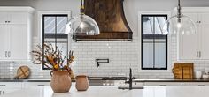 two vases with flowers sit on the kitchen counter