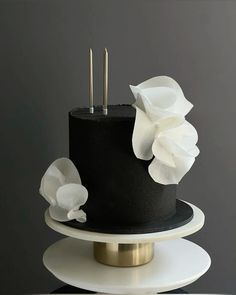 a three tiered black and white cake with flowers on top