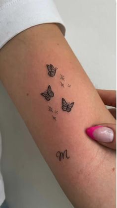 a woman's arm with butterflies and the letter m tattooed on her left side