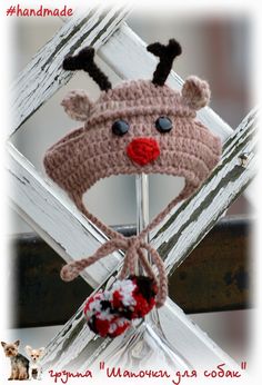 a crocheted reindeer hat hanging on a wooden fence