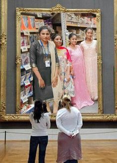 three women standing in front of a large painting on display at an art museum,