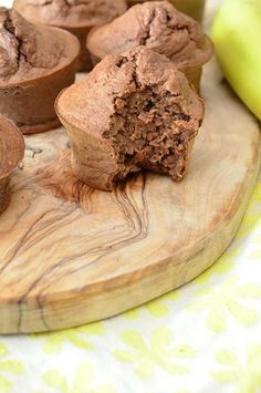 several chocolate muffins on a wooden board next to bananas