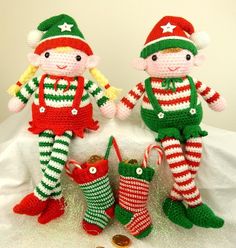 two crocheted christmas dolls sitting next to each other with candy canes in their hands