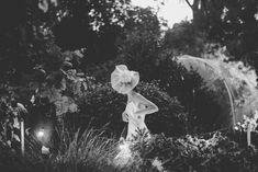 black and white photograph of a woman in a garden with an umbrella over her head