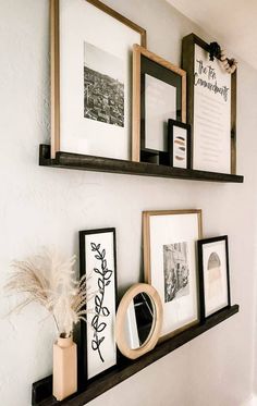 some framed pictures are hanging on the wall next to other frames and vases with plants in them