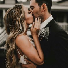 a man and woman kissing each other in front of a car with their hands on the forehead