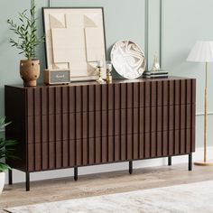 a brown dresser sitting next to a lamp on top of a wooden floor