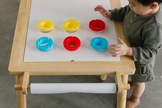 a young child playing with plastic cups on a table