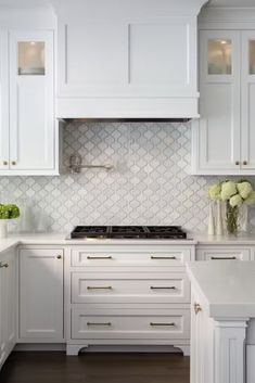 a kitchen with white cabinets and marble counter tops