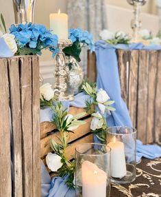 candles and flowers are sitting on the table in front of wooden crates with blue cloths