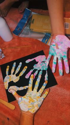 two children's hands are covered in colorful handprints on an orange blanket