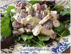 a salad with chicken, grapes and lettuce on a blue and white plate