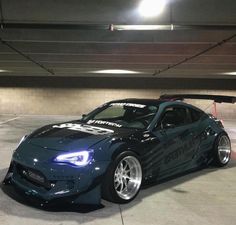 a blue sports car parked in an underground parking garage with lights on it's roof