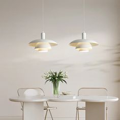 a white table with two chairs and a potted plant