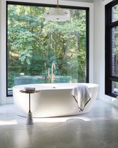 a white bath tub sitting next to a window in a room with lots of windows