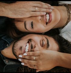 a man and woman laying on top of each other with their hands covering their eyes