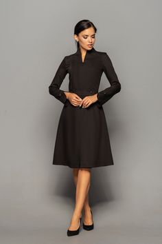 "A beautiful structured dress featuring high neck collar, a-line silhouette, and long sleeves. - high neck (stand collar) - trapeze skirt with inverted front pleat - long sleeves with elegant cuffs - knee length (midi) - a line silhouette - the dress is decorated with high-quality metal buttons Perfect as party, modest bridesmaid or elegant office dress. Seasons: autumn, winter, spring. Color: Black Fiber: viscose - 60%, elastan - 5%, polyester - 35% Concealed back zipper closure For Size S (6 U Dresses With Sleeves Elegant, Cocktail Dress Classy Evening, Elegant Purple Dresses, Formal Wedding Guest Dresses, Unique Cocktail Dresses, Stand Collar Dress, Little Black Cocktail Dress, Mandarin Collar Dress, Beautiful Cocktail Dresses