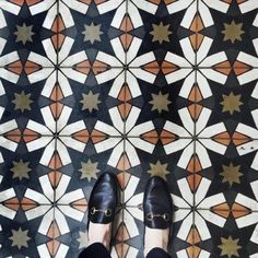 a person wearing black shoes standing in front of a tiled floor with stars on it