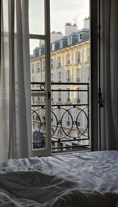 a bed sitting in front of a window next to a tall building with lots of windows