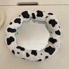 a cow print toilet seat cover sitting on top of a white counter next to a mirror