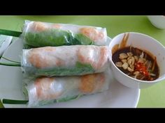 three rolls on a plate with dipping sauce next to some rice and beans in a bowl