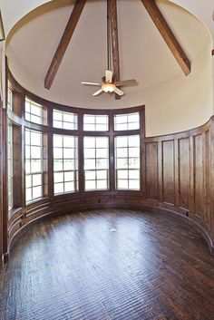 an empty room with wood paneling and a ceiling fan