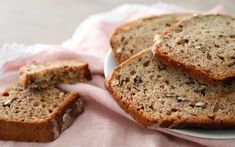 slices of banana bread on a white plate with pink cloth and napkins next to it