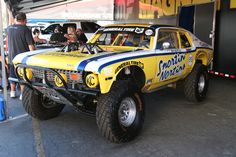 a yellow truck with big tires parked in a garage