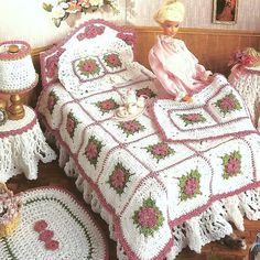 a doll sitting on top of a bed next to two crocheted bedspreads