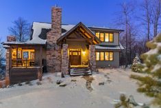 a house that has snow on the ground in front of it and trees around it