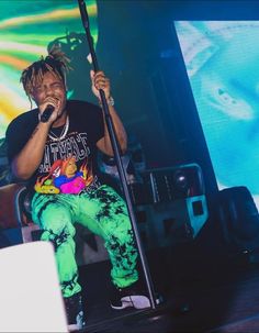 a man sitting on top of a stage holding a microphone