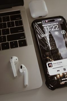 an iphone and ear buds sitting on top of a table next to a laptop computer