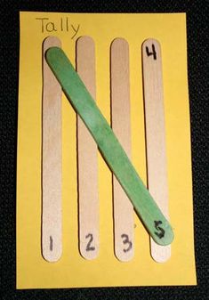 popsicle with numbers on it sitting in front of a yellow piece of paper that says, totally