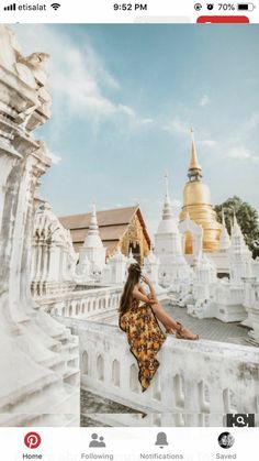 a woman sitting on top of a white building next to a golden pagoda in the background