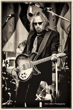 a man playing an electric guitar on stage with his arms in the air greeting card