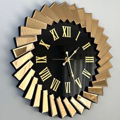 a black and gold wall clock with roman numerals on the face is shown